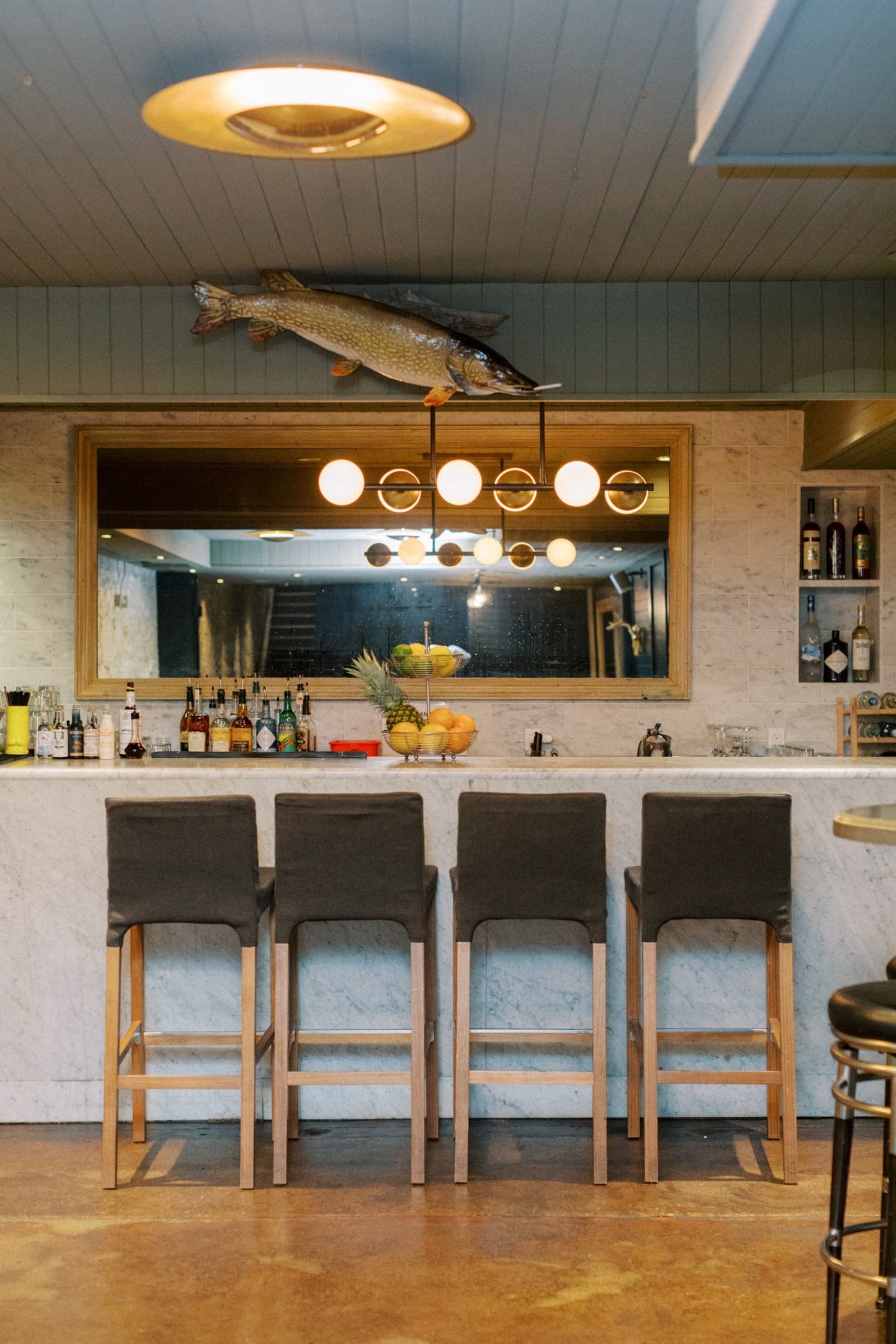 The Loon Room bar interior with marble counter, mounted fish, warm lighting